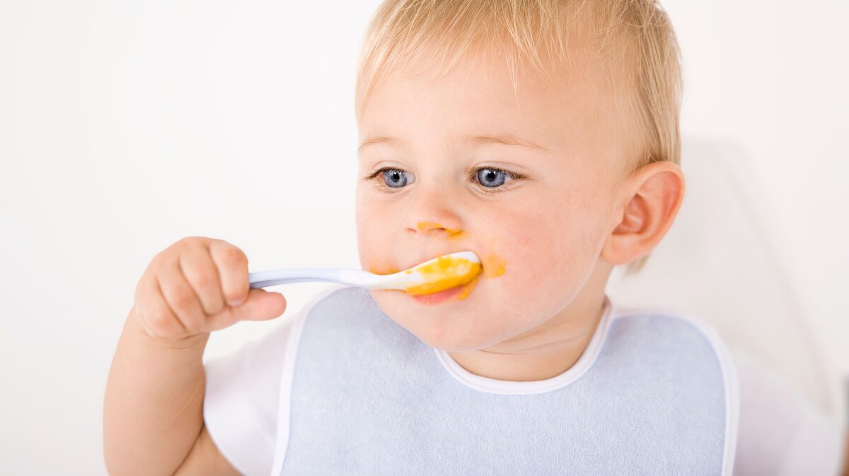 Malé dítě se samo krmí lžičkou s pyré